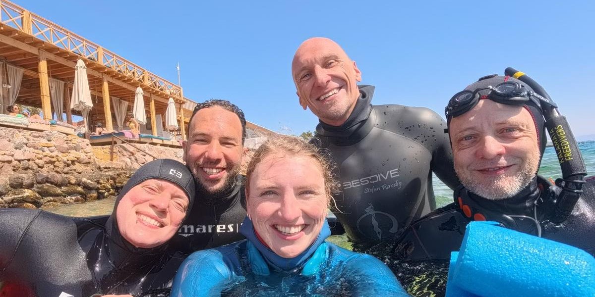 The whole crew smiling together on the buoy after an open-water session